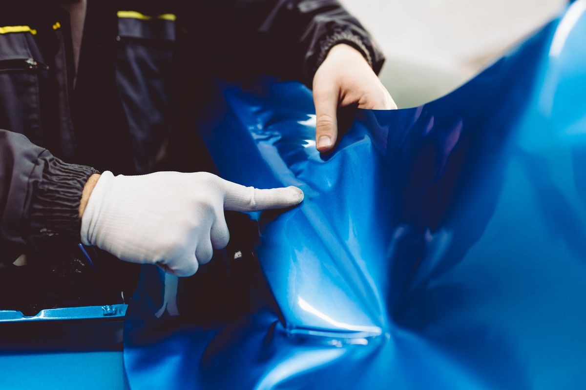 Car wrapping specialist putting vinyl foil or film on car. Selective focus. 